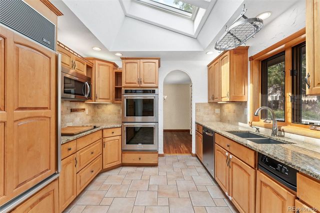 a kitchen with stainless steel appliances granite countertop a refrigerator a sink dishwasher a stove with white cabinets and wooden floor