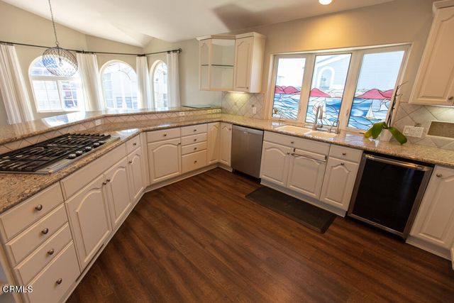 a kitchen with granite countertop a stove a sink and dishwasher wooden cabinets with wooden floor
