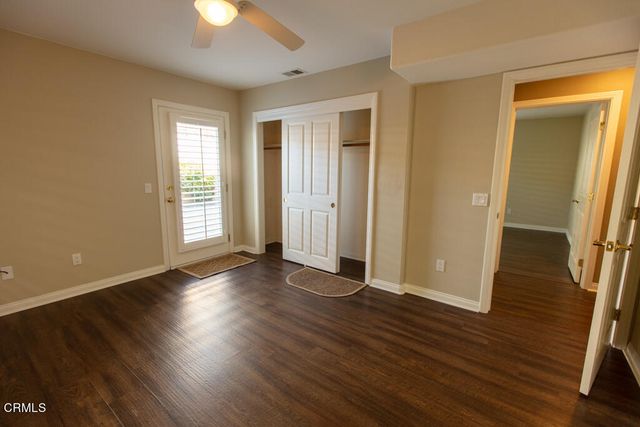 an empty room with wooden floor and a ceiling fan