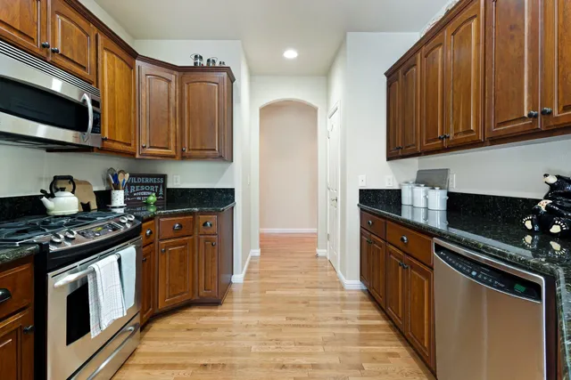 a kitchen with stainless steel appliances granite countertop a stove a sink dishwasher and a microwave oven with cabinets