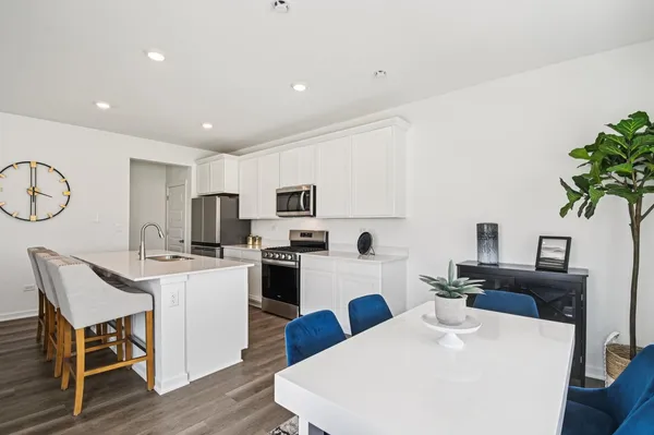 a kitchen with stainless steel appliances kitchen island granite countertop a refrigerator a stove top oven a sink dishwasher and white appliances with wooden floor