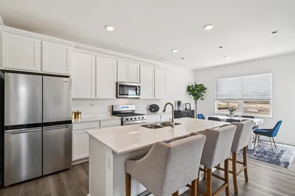 a kitchen with stainless steel appliances granite countertop a dining table chairs refrigerator and cabinets