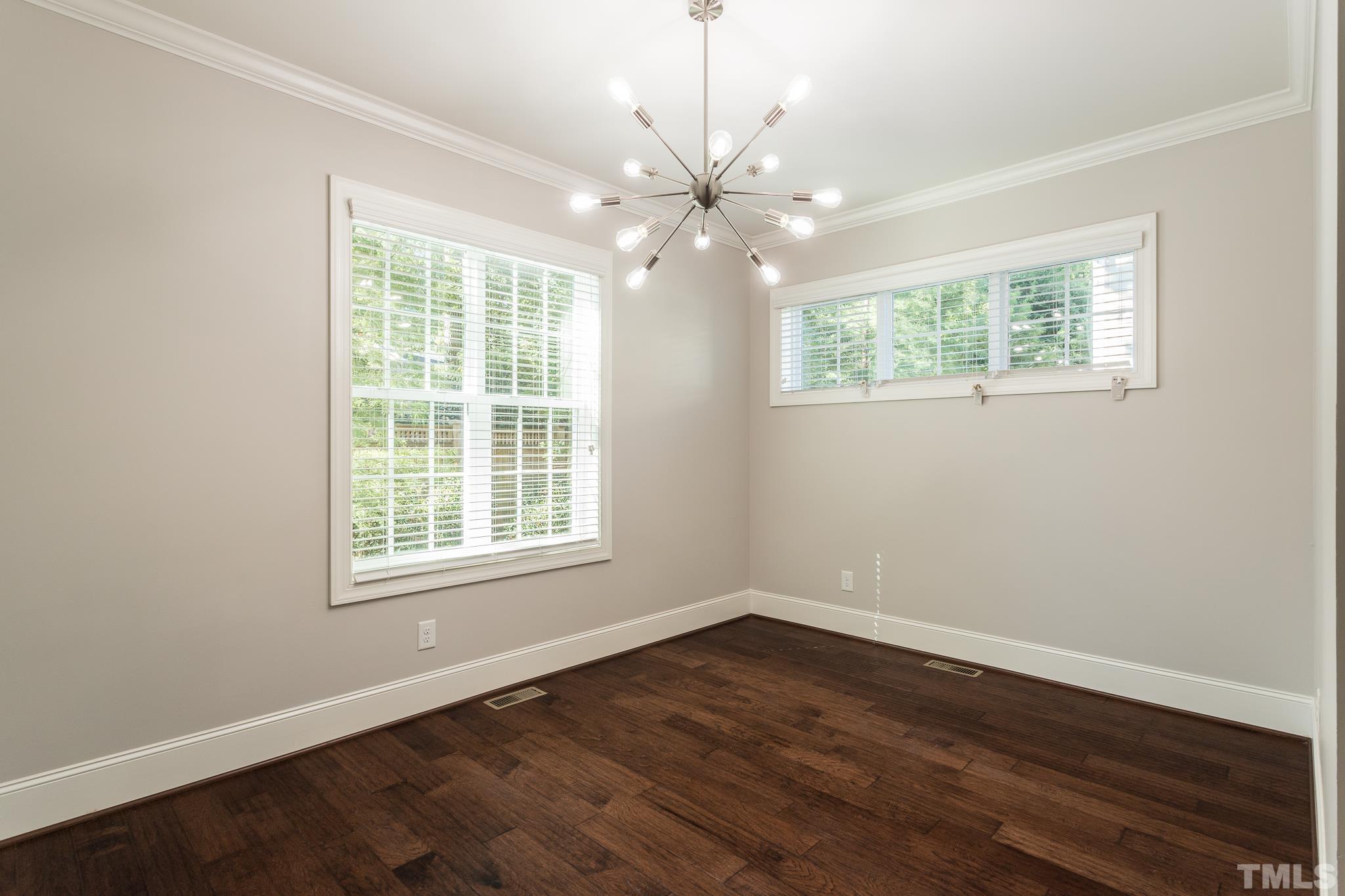 2809 Plumfield Place Raleigh, NC 27607 - Photo 4 of 25 an empty room with wooden floor chandelier fan and windows