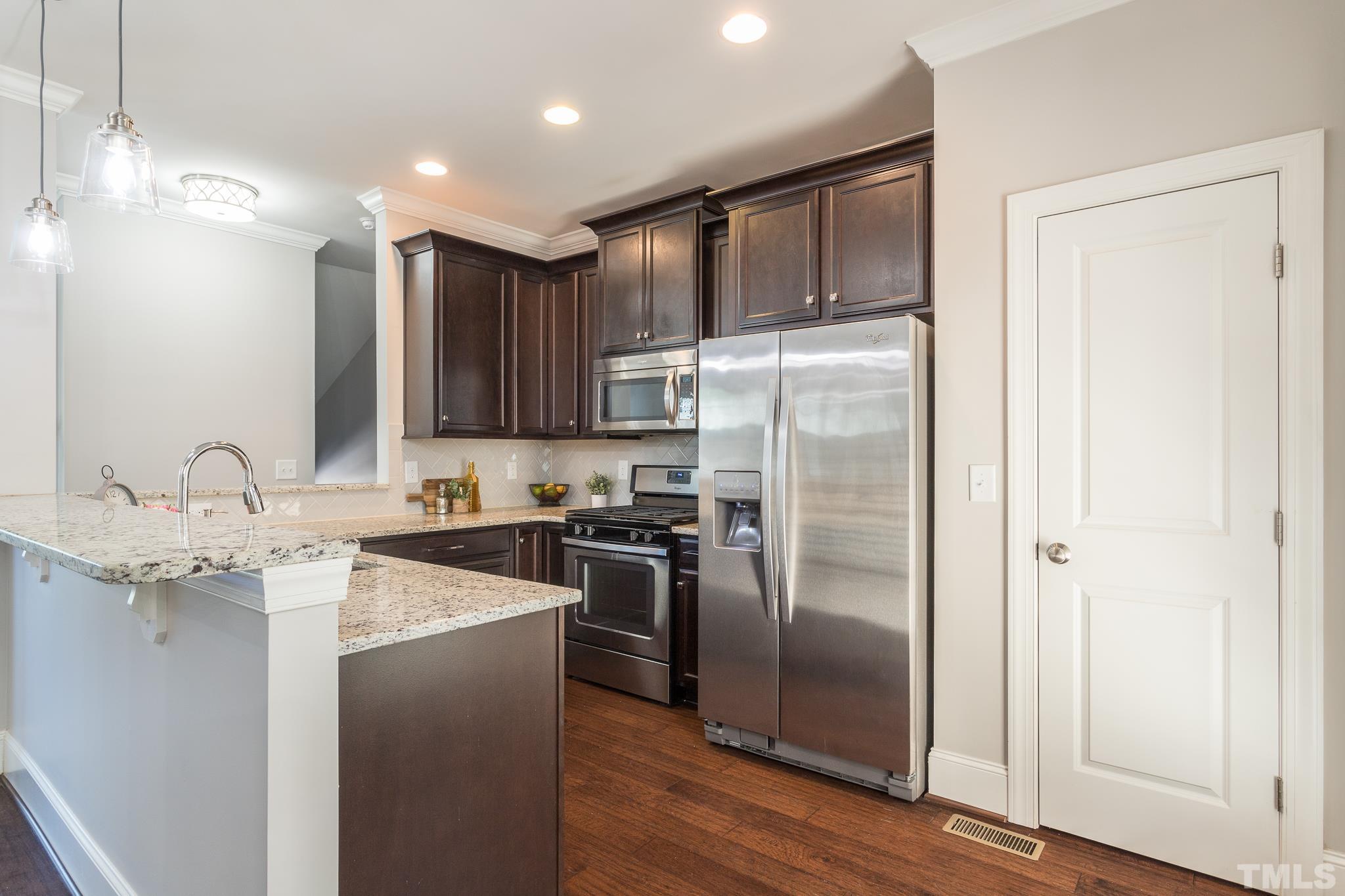 2809 Plumfield Place Raleigh, NC 27607 - Photo 7 of 25 a kitchen with granite countertop stainless steel appliances a refrigerator a sink and cabinets