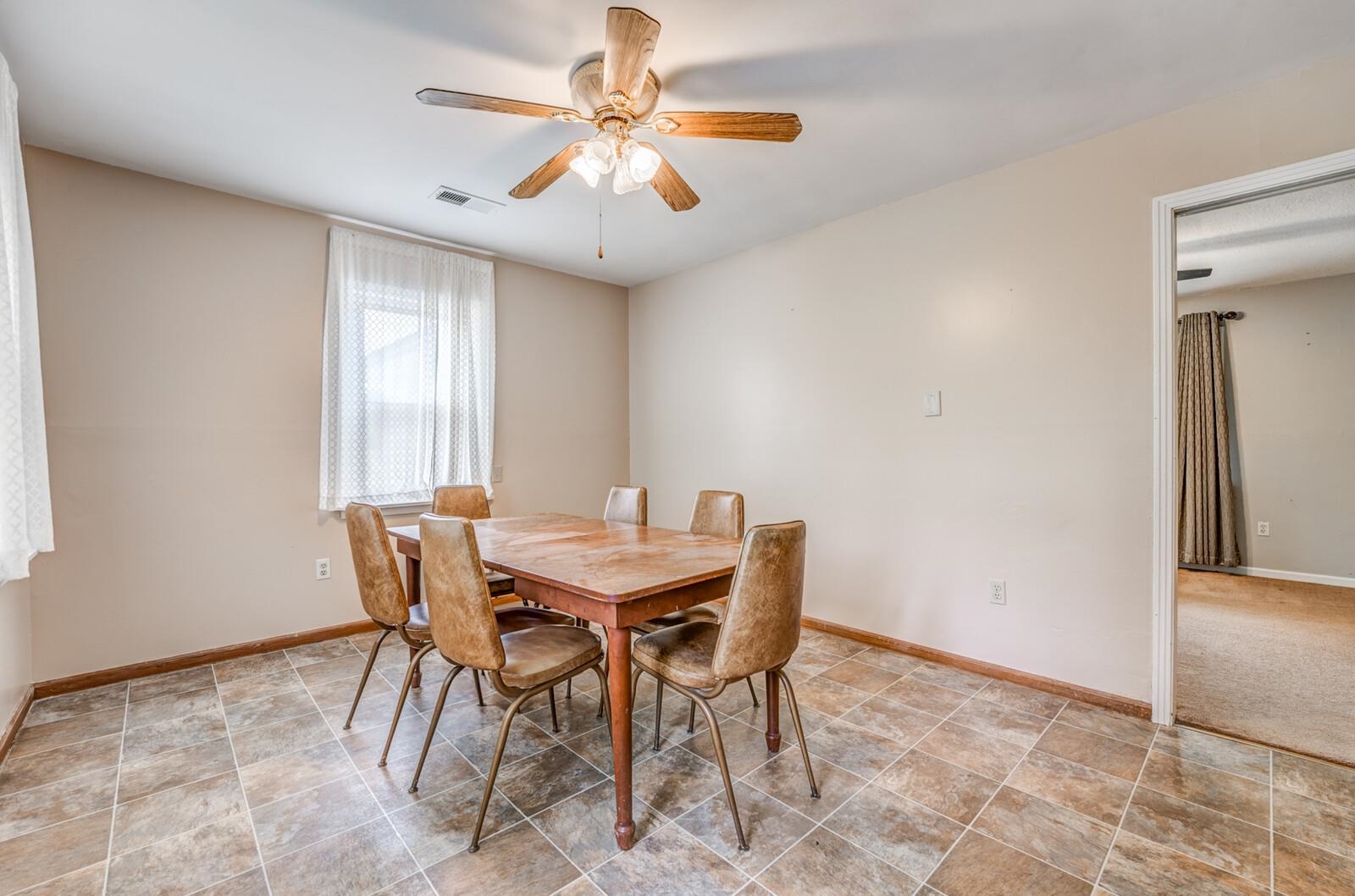 6125 Warren Road Oakland, TN 38060 - Photo 12 of 40 Dining area featuring patterned tile flooring, a window with sheer curtains, a ceiling fan with integrated lighting, and a doorway opening to an additional room