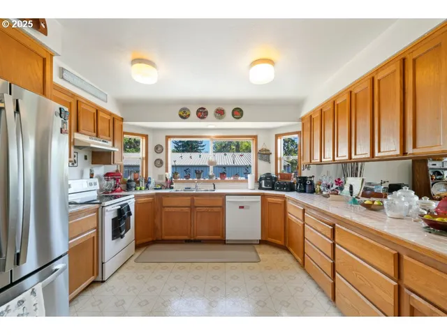 a kitchen with stainless steel appliances granite countertop a refrigerator a sink a stove and cabinets
