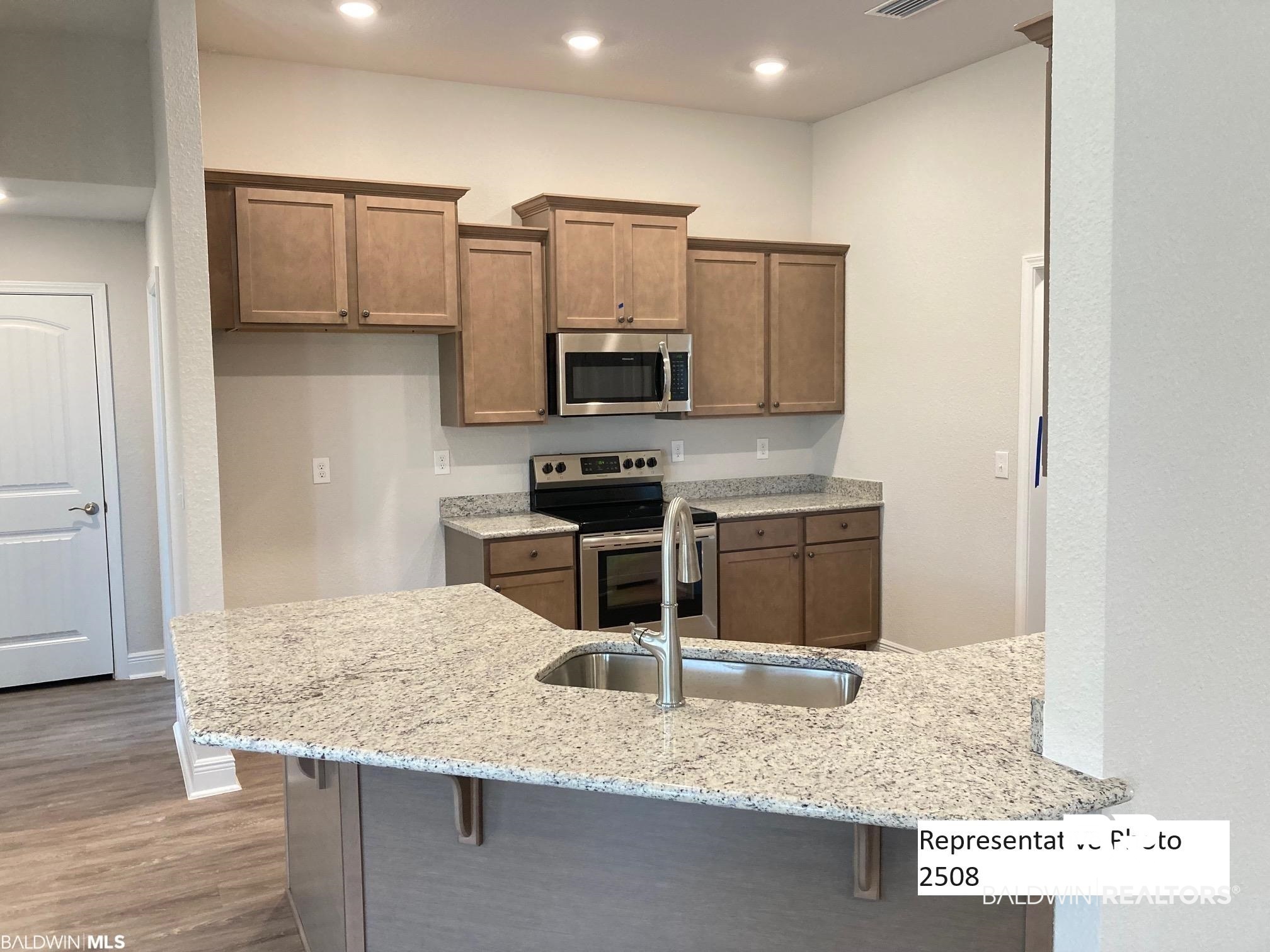 2201 Pollard Road Daphne, AL 36526 - Photo 7 of 15 Kitchen featuring stainless steel appliances, a kitchen bar, sink, light hardwood / wood-style flooring, and kitchen peninsula