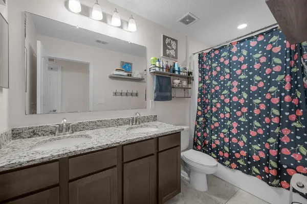 a bathroom with a granite countertop sink mirror vanity and toilet