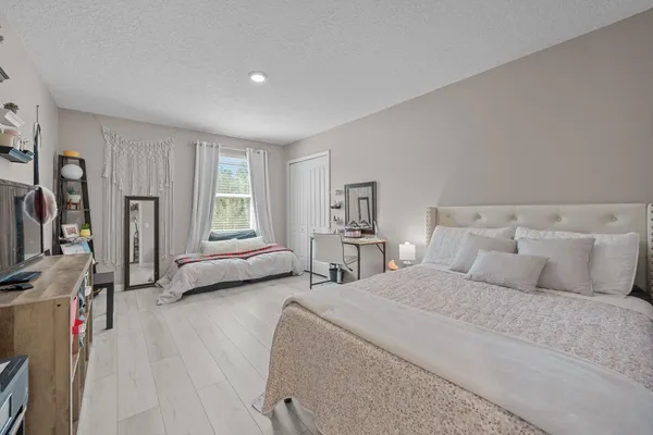 a bedroom with bed and a large mirror next to a window