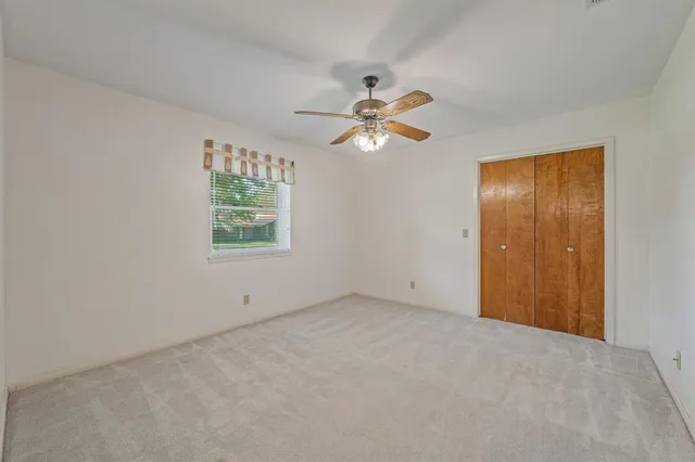 an empty room with a window and a fan