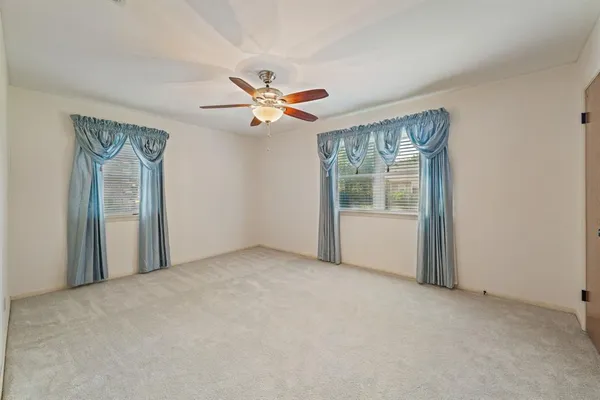 an empty room with fan and windows