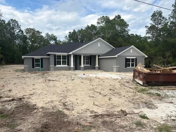 a front view of house with yard and trees in the background