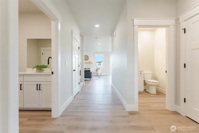 a view of a hallway with wooden floor and a bathroom