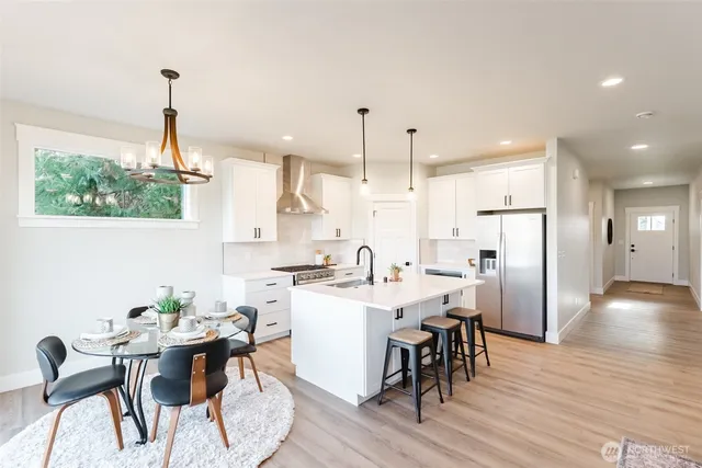 a kitchen with stainless steel appliances a dining table chairs stove and kitchen view