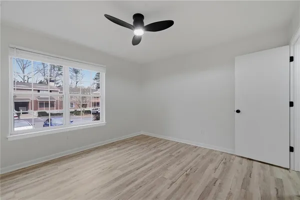 a view of an empty room with a window and wooden floor