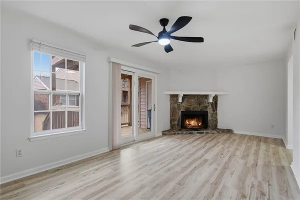 a view of an empty room with wooden floor fireplace and a window
