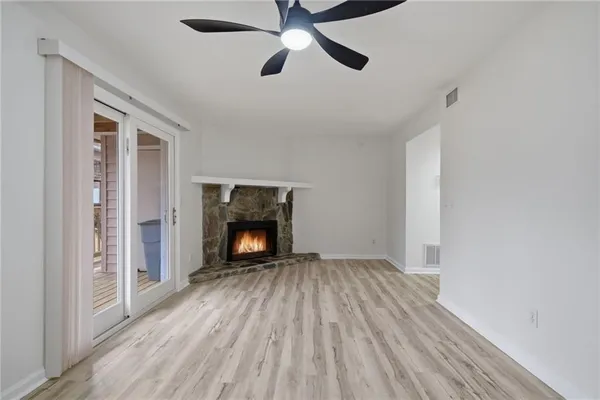 a view of an empty room with wooden floor fireplace and a window