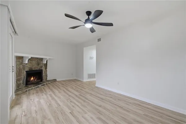 a view of an empty room with wooden floor and a fireplace