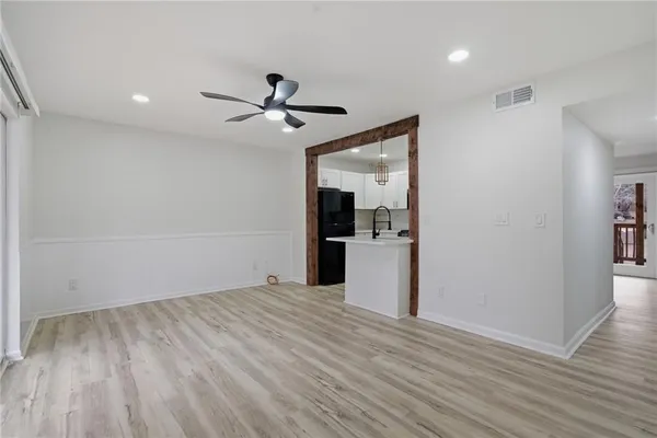 a view of empty room with wooden floor and kitchen view