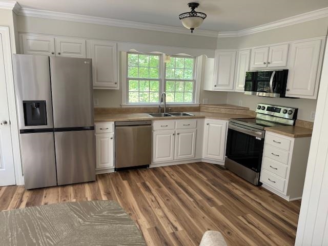 1409 Roper Road Bolivar, TN 38008 - Photo 9 of 33 Kitchen featuring white cabinets, stainless steel appliances, sink, dark hardwood / wood-style floors, and ornamental molding