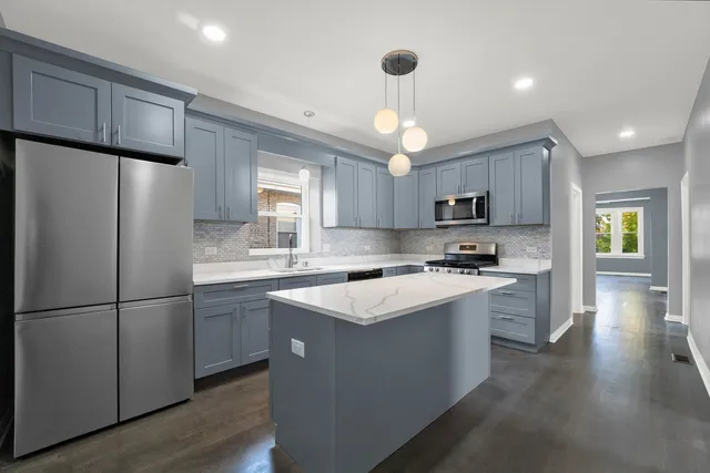 a kitchen with stainless steel appliances granite countertop a refrigerator a sink dishwasher a stove a refrigerator and white cabinets with wooden floor