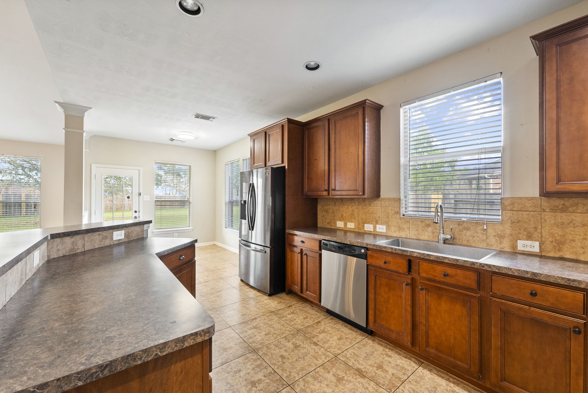 9526 Tartan Manor Street Spring, TX 77379 - Photo 13 of 42 a large kitchen with stainless steel appliances granite countertop a refrigerator a sink dishwasher a stove a dining table and chairs with wooden floor