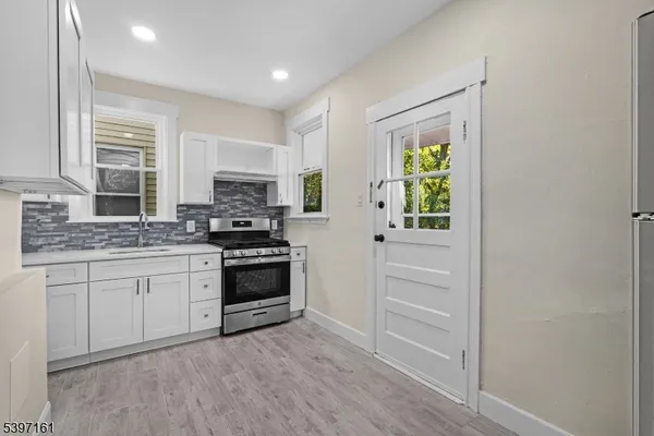 a kitchen with granite countertop a stove a sink and a refrigerator