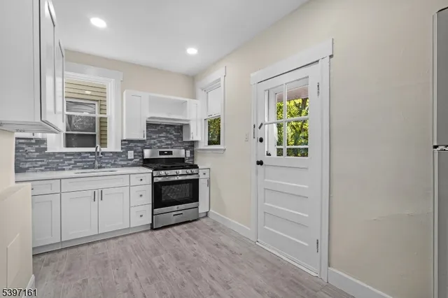 a kitchen with granite countertop a stove a sink and a refrigerator