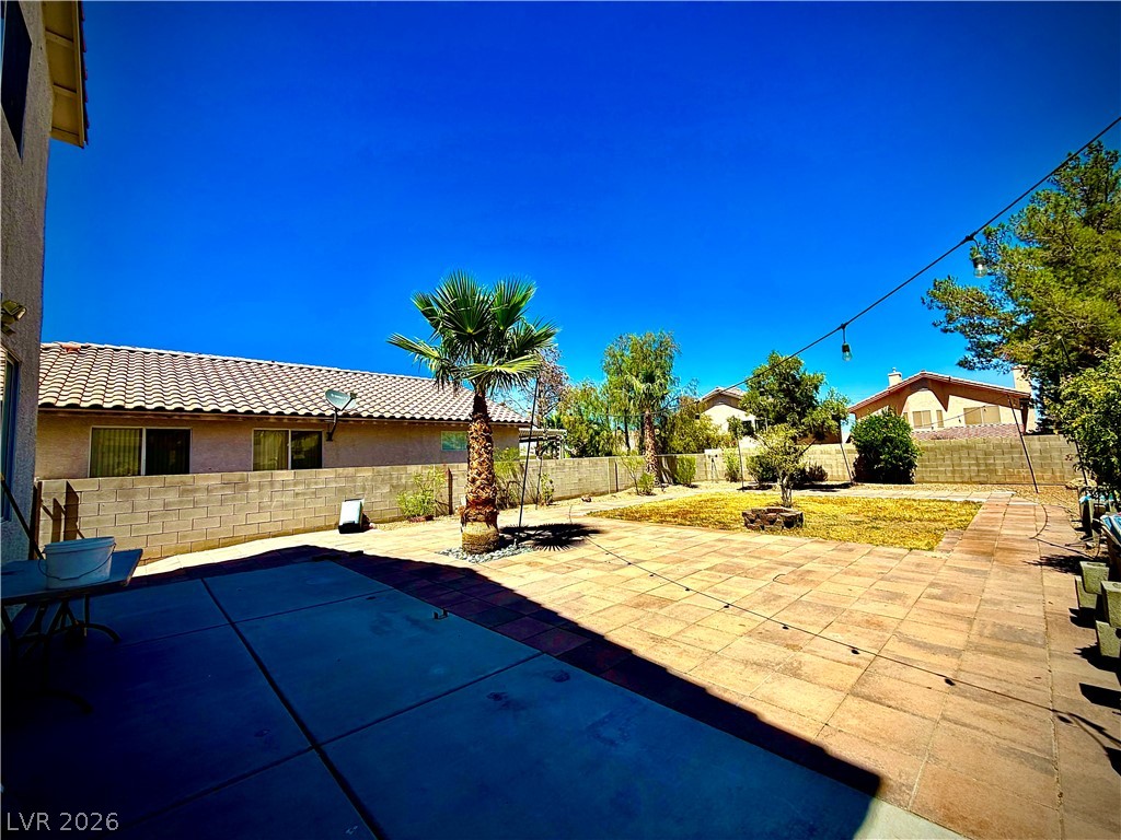 3936 Gold Point Street Las Vegas, NV 89129 - Photo 20 of 23 A spacious backyard retreat features a paved patio, lush green lawn, and mature palm trees.