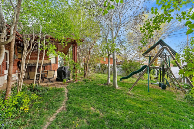 321 West 2575 North Sunset, UT 84015 - Photo 30 of 30 Expansive backyard featuring a lush lawn, mature trees, and a dedicated play structure with a slide