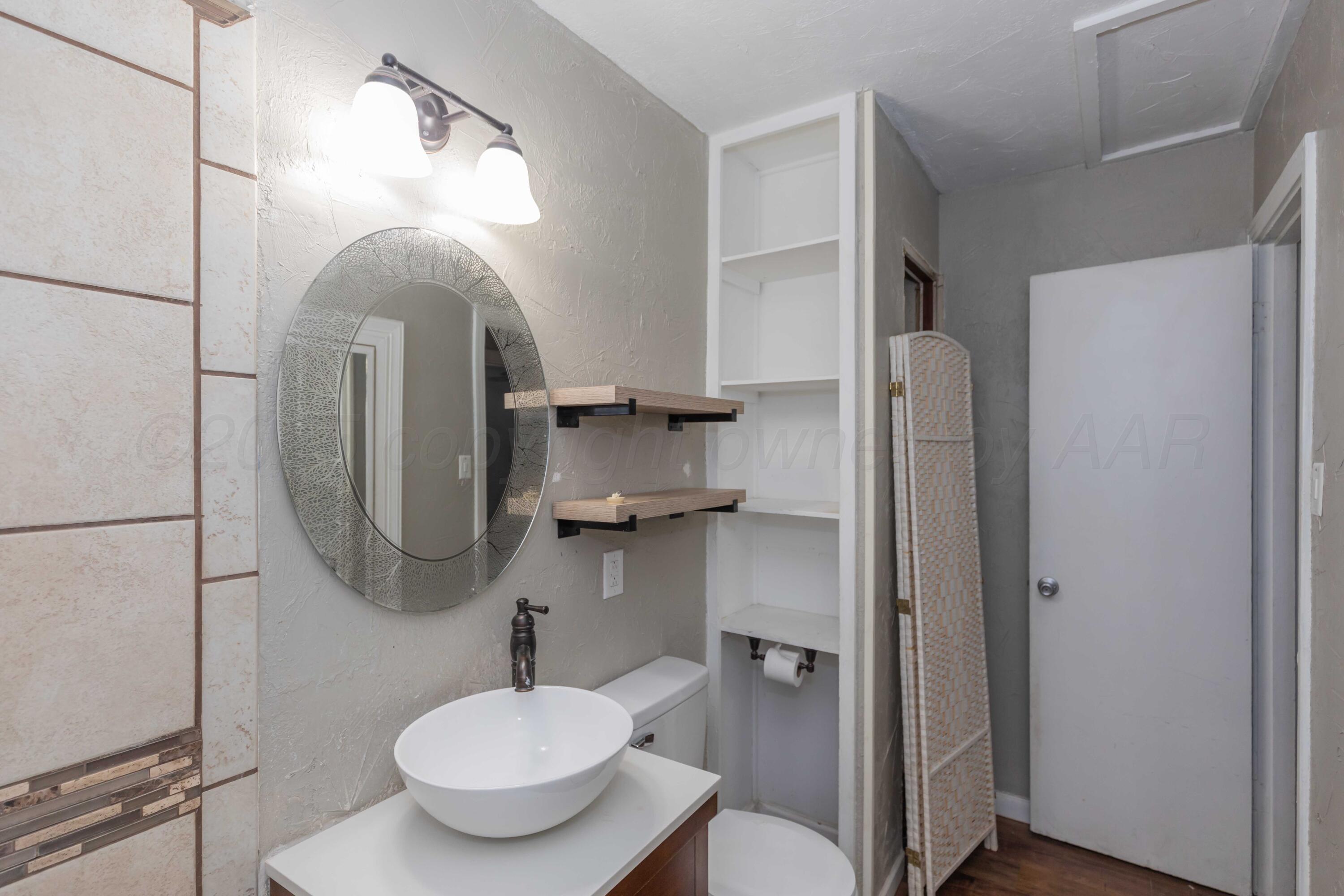 4516 South Bonham Street Amarillo, TX 79110 - Photo 19 of 30 a bathroom with a toilet sink and mirror
