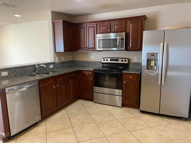 a kitchen with stainless steel appliances granite countertop a stove a refrigerator and a sink