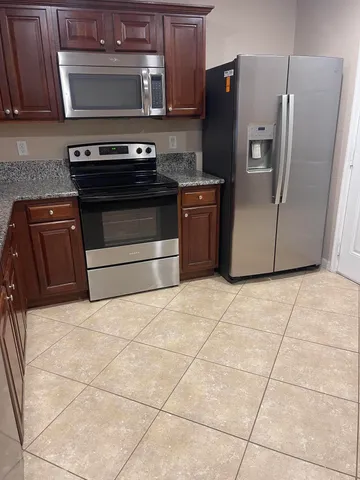 a kitchen with stainless steel appliances granite countertop a stove a refrigerator and a cabinets