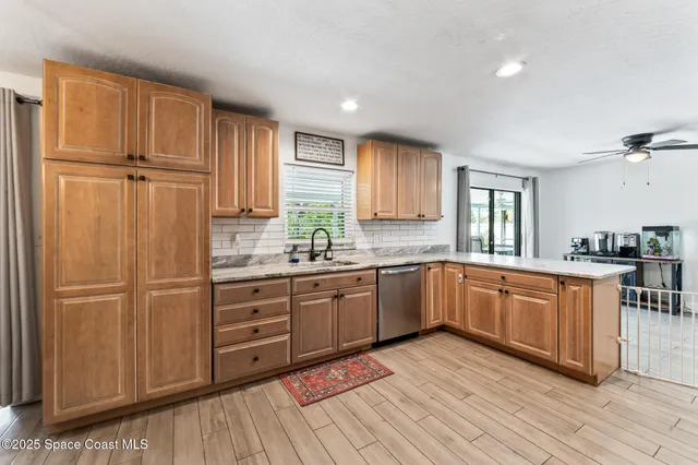 a kitchen with stainless steel appliances granite countertop a refrigerator a sink dishwasher and white cabinets with wooden floor