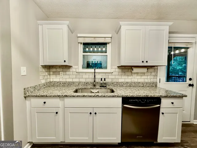 a kitchen with granite countertop white cabinets and a sink