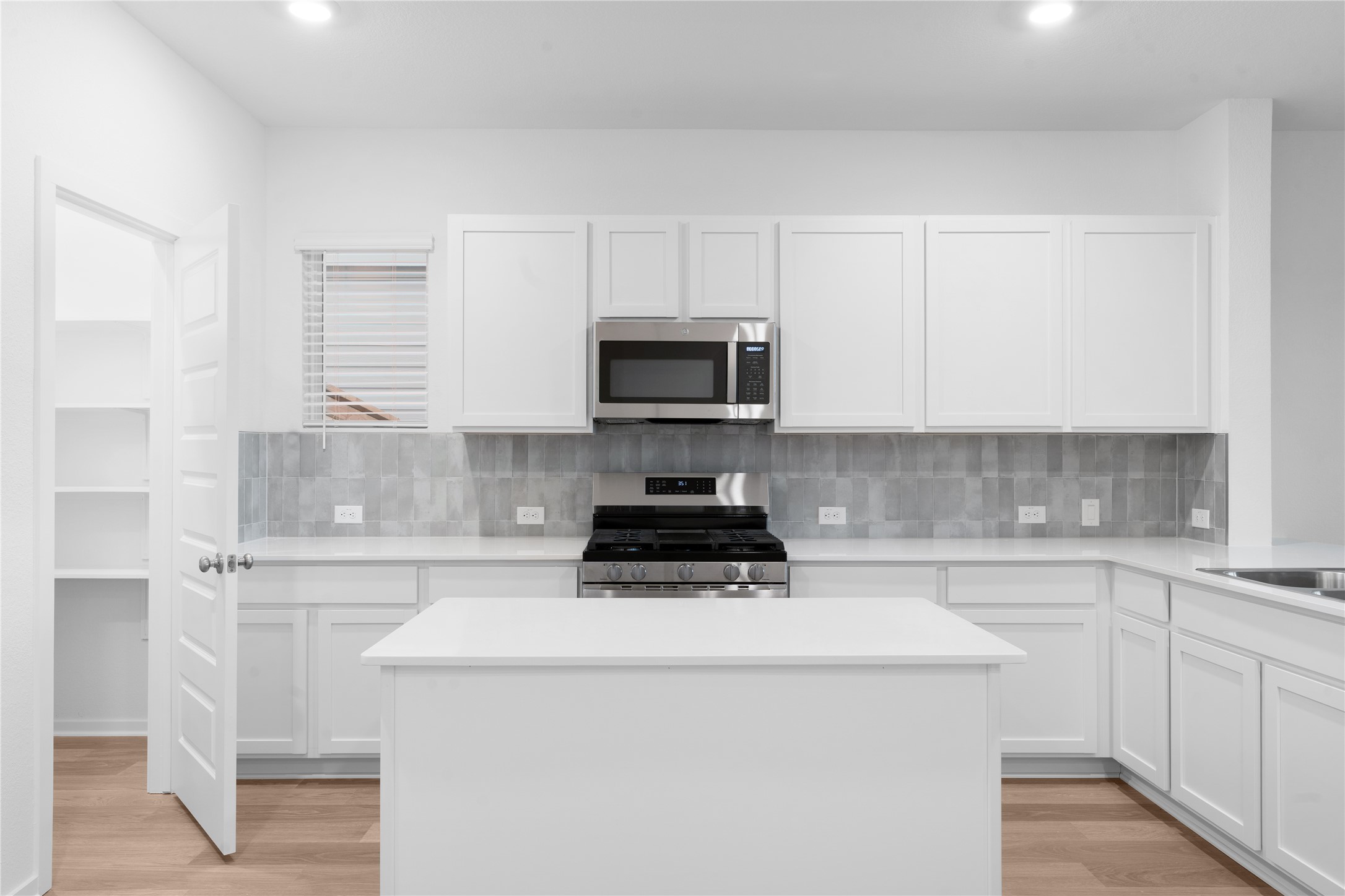 25612 Wheat Seed Lane Elgin, TX 78621 - Photo 12 of 26 a kitchen with a sink and a stove top oven with white cabinets