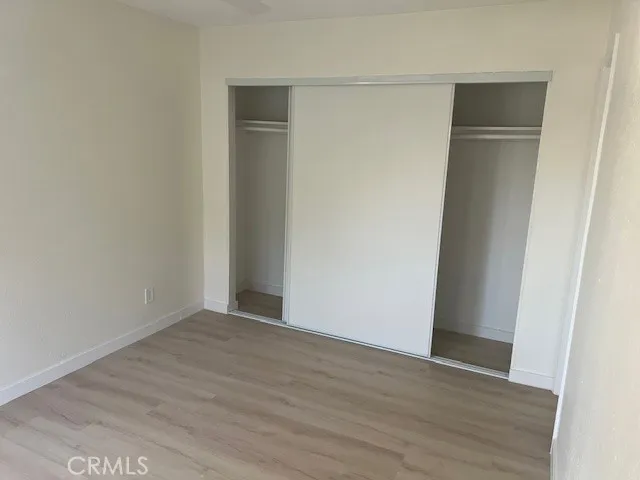 an empty room with wooden floor ceiling fan and window