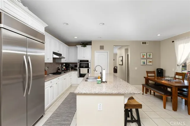 a kitchen with stainless steel appliances kitchen island granite countertop a refrigerator and a sink