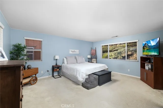 a spacious bedroom with a bed and a flat screen tv