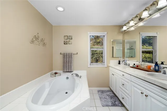 a bathroom with a double vanity sink a large mirror and a bathtub
