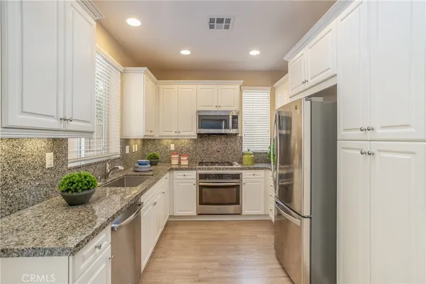 a kitchen with stainless steel appliances granite countertop a refrigerator sink and stove