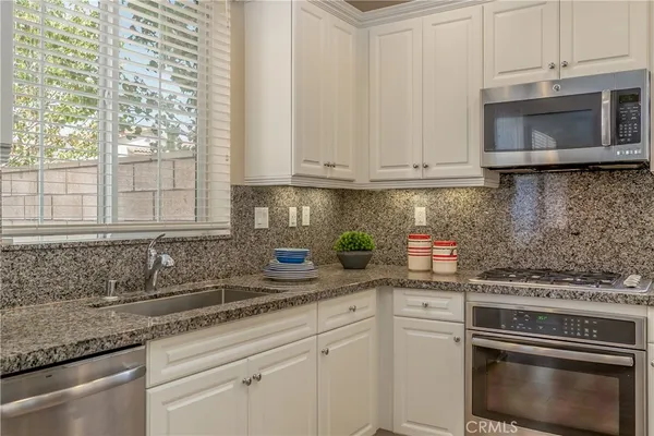 a kitchen with stainless steel appliances granite countertop a sink a stove and a microwave