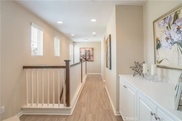 a view of a hallway to a livingroom with wooden floor and stairs