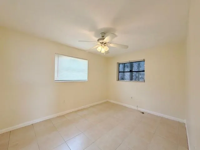 an empty room with a chandelier fan and windows