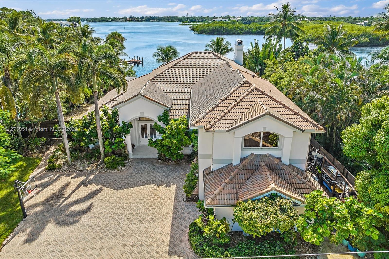 9460 Southeast Point Terrace Jupiter, FL 33469 - Photo 2 of 51 a front view of a house with a yard and potted plants