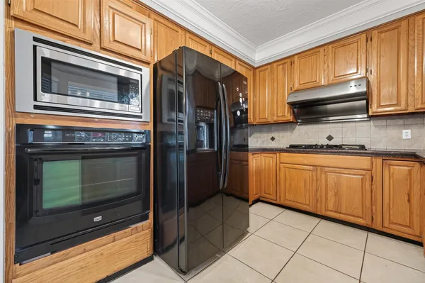 a kitchen with granite countertop a refrigerator stove and cabinets
