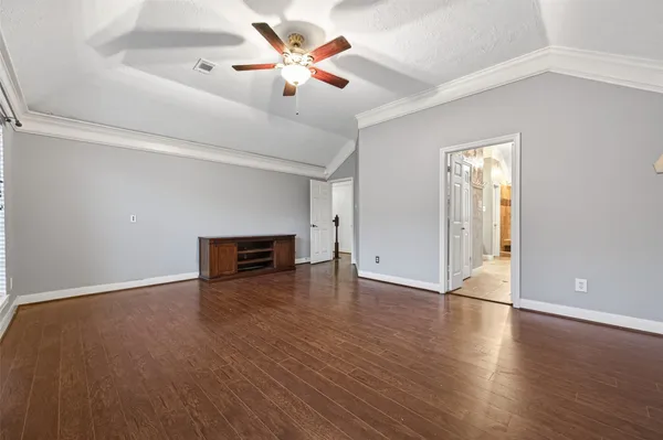 an empty room with wooden floor and ceiling fan