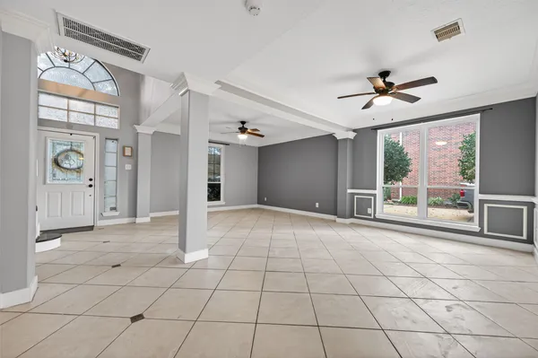 a view of an empty room with window and chandelier fan