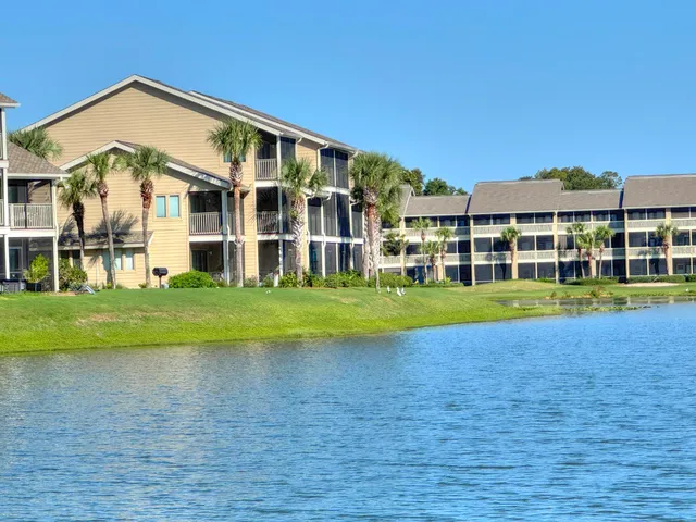 a view of a building with a big yard and large trees