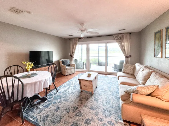 a living room with furniture a flat screen tv and a large window